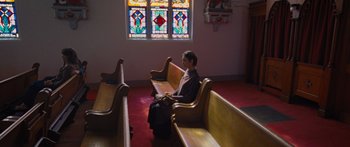 Movie still from “To the Wonder” (2012), directed by Terrence Malick – A woman sitting on a bench in front of a stained glass window; Wide shot, Low angle