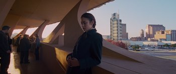 Movie still from “To the Wonder” (2012), directed by Terrence Malick – A woman standing in front of a window with buildings in the background; Medium shot, Low angle