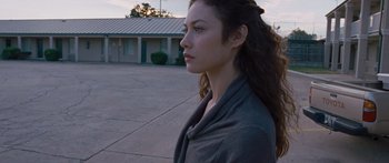 Movie still from “To the Wonder” (2012), directed by Terrence Malick – A woman standing in front of a building looking to her left; Close Up shot, Over the shoulder angle