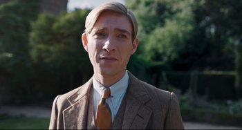 Movie still from “Goodbye Christopher Robin” (2017), directed by Simon Curtis – A man wearing a suit and tie in front of trees; Close Up shot, Over the shoulder angle
