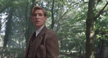 Movie still from “Goodbye Christopher Robin” (2017), directed by Simon Curtis – A man in a suit and tie standing in front of trees; Medium shot, Low angle