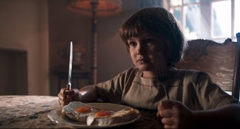 Movie still from “Goodbye Christopher Robin” (2017), directed by Simon Curtis – A young child sitting at a table with a plate of eggs and a knife; Close Up shot, High angle