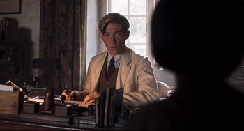 Movie still from “Goodbye Christopher Robin” (2017), directed by Simon Curtis – A man sitting at a table writing on a piece of paper; Medium shot, Over the shoulder angle