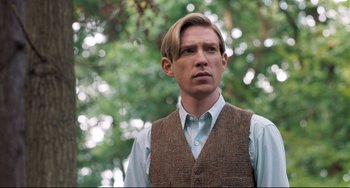 Movie still from “Goodbye Christopher Robin” (2017), directed by Simon Curtis – A man with blonde hair wearing a brown vest and a blue shirt; Close Up shot, Low angle