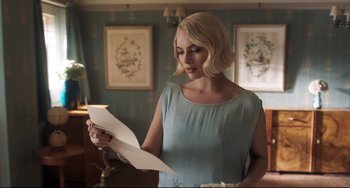 Movie still from “Goodbye Christopher Robin” (2017), directed by Simon Curtis – A woman in a blue dress looking down at a paper; Medium shot, Over the shoulder angle