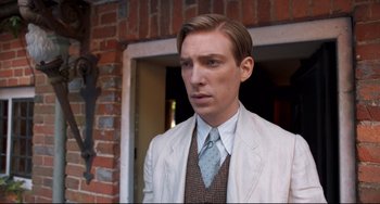 Movie still from “Goodbye Christopher Robin” (2017), directed by Simon Curtis – A man wearing a suit and tie standing in front of a brick building; Close Up shot, Low angle