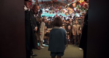 Movie still from “Goodbye Christopher Robin” (2017), directed by Simon Curtis – A group of people standing in a room with leaves; Wide shot, Over the shoulder angle