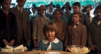 Movie still from “Goodbye Christopher Robin” (2017), directed by Simon Curtis – A group of people standing around a table with food on top of it; Medium shot, High angle