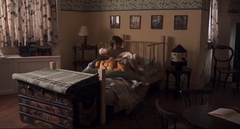Movie still from “Goodbye Christopher Robin” (2017), directed by Simon Curtis – A person laying in bed with a bunch of bread; Wide shot, High angle