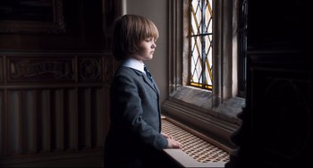 Movie still from “Goodbye Christopher Robin” (2017), directed by Simon Curtis – A boy in a suit and tie looking out of a window; Medium shot, Low angle