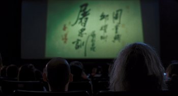 Movie still from “Goodbye, Dragon Inn” (2003), directed by Tsai Ming-liang – A man and a woman sitting in front of a projector screen; Close Up shot, Over the shoulder angle