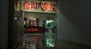 Movie still from “Goodbye, Dragon Inn” (2003), directed by Tsai Ming-liang – A person standing in front of an asian restaurant; Wide shot, Low angle