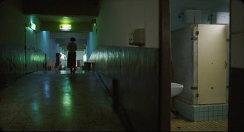 Movie still from “Goodbye, Dragon Inn” (2003), directed by Tsai Ming-liang – A person is standing in a room with a sink; Extreme Wide shot, High angle