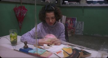Movie still from “Goodbye, Dragon Inn” (2003), directed by Tsai Ming-liang – A woman sitting at a table with papers on the table; Medium shot, High angle