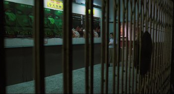 Movie still from “Goodbye, Dragon Inn” (2003), directed by Tsai Ming-liang – A man standing in front of a wall with posters on it; Wide shot, High angle