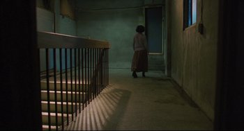 Movie still from “Goodbye, Dragon Inn” (2003), directed by Tsai Ming-liang – A woman walking down the stairs of a building; Wide shot, Low angle