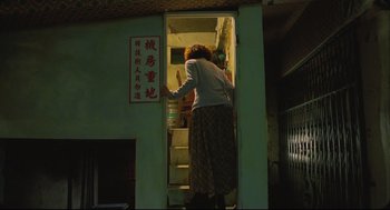 Movie still from “Goodbye, Dragon Inn” (2003), directed by Tsai Ming-liang – A woman standing at the bottom of a staircase; Wide shot, Low angle