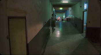 Movie still from “Goodbye, Dragon Inn” (2003), directed by Tsai Ming-liang – A person standing in a hallway with a green light; Extreme Wide shot, High angle
