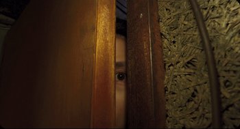 Movie still from “Goodbye, Dragon Inn” (2003), directed by Tsai Ming-liang – A young child peeks out from behind a wooden wall; Extreme Close Up shot, Low angle