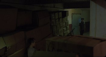 Movie still from “Goodbye, Dragon Inn” (2003), directed by Tsai Ming-liang – A man sitting in front of boxes in a room; Wide shot, Low angle