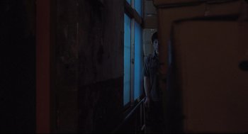 Movie still from “Goodbye, Dragon Inn” (2003), directed by Tsai Ming-liang – A man standing in front of a window in a dark room; Wide shot, Over the shoulder angle