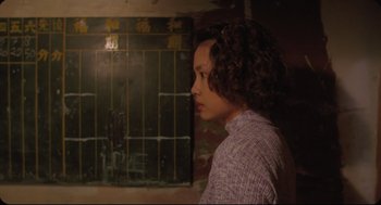 Movie still from “Goodbye, Dragon Inn” (2003), directed by Tsai Ming-liang – A woman with curly hair is standing in front of a window; Medium shot, Over the shoulder angle