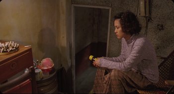 Movie still from “Goodbye, Dragon Inn” (2003), directed by Tsai Ming-liang – A woman sitting in a room holding a flashlight; Medium shot, High angle