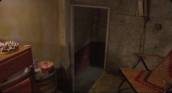 Movie still from “Goodbye, Dragon Inn” (2003), directed by Tsai Ming-liang – An open door in a room with a table and chairs in it; Wide shot, High angle