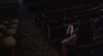 Movie still from “Goodbye, Dragon Inn” (2003), directed by Tsai Ming-liang – A woman sitting on a chair in an empty theater; Wide shot, High angle