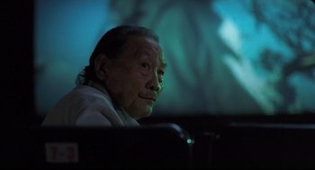 Movie still from “Goodbye, Dragon Inn” (2003), directed by Tsai Ming-liang – An older man sitting in front of a projection screen; Close Up shot, Low angle