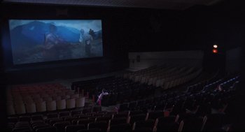 Movie still from “Goodbye, Dragon Inn” (2003), directed by Tsai Ming-liang – A person is standing in front of a screen in an auditorium; Extreme Wide shot, High angle