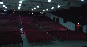 Movie still from “Goodbye, Dragon Inn” (2003), directed by Tsai Ming-liang – Rows of red chairs in a large auditorium; Extreme Wide shot, High angle