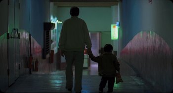 Movie still from “Goodbye, Dragon Inn” (2003), directed by Tsai Ming-liang – An adult and a small child walking down a hallway at night; Wide shot, Low angle