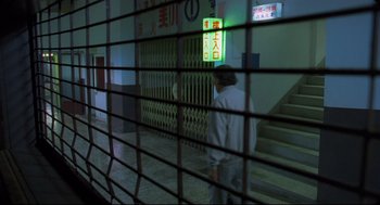 Movie still from “Goodbye, Dragon Inn” (2003), directed by Tsai Ming-liang – A man walking down a staircase in a building; Wide shot, High angle