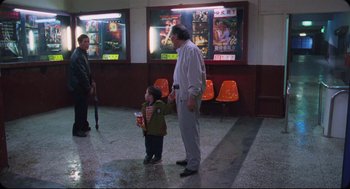 Movie still from “Goodbye, Dragon Inn” (2003), directed by Tsai Ming-liang – An older man and a young boy are standing in a movie theater; Wide shot, High angle