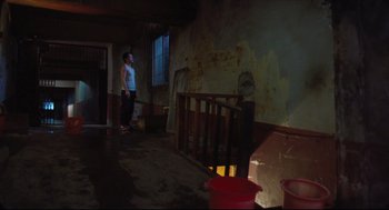 Movie still from “Goodbye, Dragon Inn” (2003), directed by Tsai Ming-liang – A person standing in a room with a railing; Wide shot, Low angle