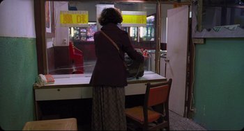 Movie still from “Goodbye, Dragon Inn” (2003), directed by Tsai Ming-liang – A woman standing in front of a store window; Wide shot, Over the shoulder angle