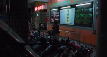 Movie still from “Goodbye, Dragon Inn” (2003), directed by Tsai Ming-liang – A woman standing in front of an asian restaurant; Wide shot, Low angle