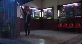Movie still from “Goodbye, Dragon Inn” (2003), directed by Tsai Ming-liang – A man standing in front of movie posters in a movie theater; Wide shot, Low angle