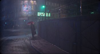 Movie still from “Goodbye, Dragon Inn” (2003), directed by Tsai Ming-liang – A person with an umbrella is walking down the street; Extreme Wide shot, Low angle