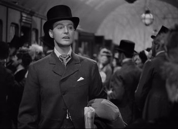 Movie still from “Goodbye, Mr. Chips” (1939), directed by Sam Wood – A black and white photo of a man in a suit and top hat; Medium shot, Over the shoulder angle