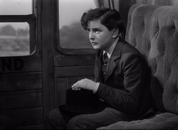 Movie still from “Goodbye, Mr. Chips” (1939), directed by Sam Wood – A young man sitting in a chair holding a hat; Medium shot, High angle