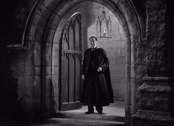 Movie still from “Goodbye, Mr. Chips” (1939), directed by Sam Wood – A man standing in front of an arched doorway; Wide shot, Low angle