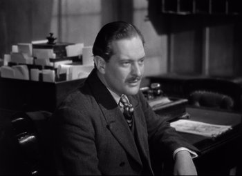 Movie still from “Goodbye, Mr. Chips” (1939), directed by Sam Wood – An older man sitting at a desk wearing a suit and tie; Close Up shot, High angle