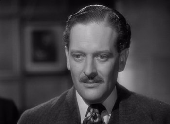 Movie still from “Goodbye, Mr. Chips” (1939), directed by Sam Wood – A man in a suit and tie looking at the camera; Close Up shot, High angle