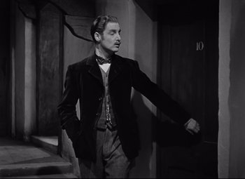 Movie still from “Goodbye, Mr. Chips” (1939), directed by Sam Wood – A black and white photo of a man in a suit and bow tie; Medium shot, Low angle