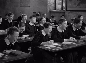Movie still from “Goodbye, Mr. Chips” (1939), directed by Sam Wood – A black and white photo of a group of students in a class room; Medium shot, High angle