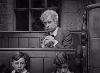 Movie still from “Goodbye, Mr. Chips” (1939), directed by Sam Wood – An older man sitting in a courtroom with two young boys; Medium shot, High angle