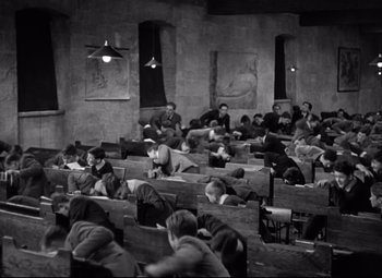 Movie still from “Goodbye, Mr. Chips” (1939), directed by Sam Wood – A black and white photo of people sitting in a classroom; Wide shot, High angle