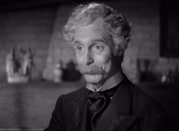 Movie still from “Goodbye, Mr. Chips” (1939), directed by Sam Wood – An older man with a mustache and curly white hair; Close Up shot, Over the shoulder angle